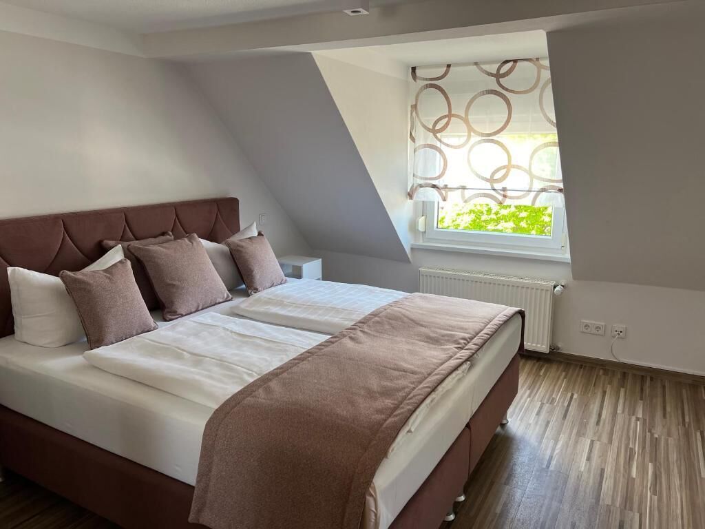 Un dormitorio con cama, ventana con vistas y radiador.