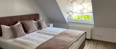 Un dormitorio con cama, ventana con vistas y radiador.