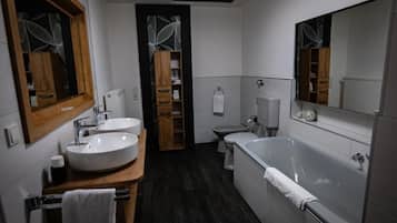 Un baño moderno con bañera, dos lavamanos y un inodoro.