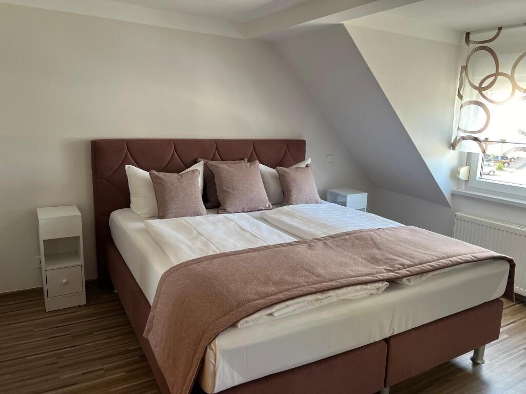 A bedroom with a bed, nightstands, a window, and a sloped ceiling.