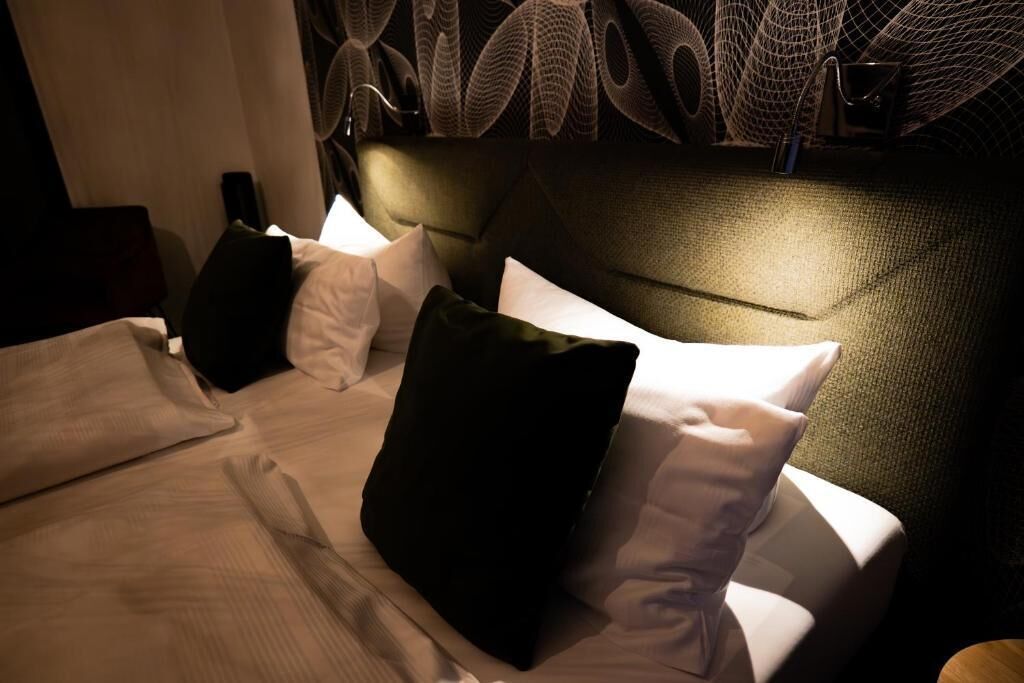 Ein Hotelzimmer mit einem Bett, Kissen und einem Kopfteil mit strukturierter Oberfläche.