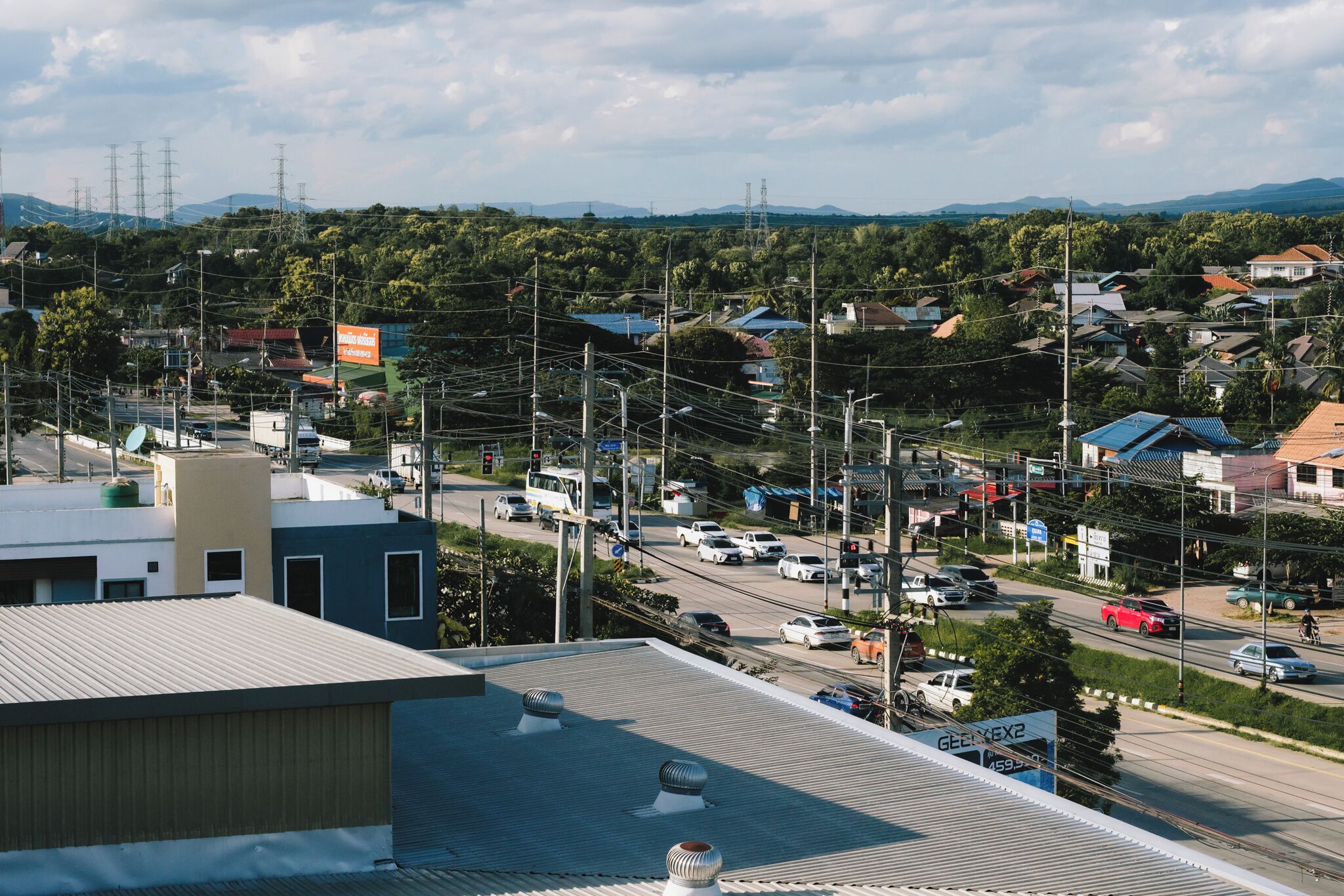 Vista de un pueblo con edificios residenciales y comerciales, una carretera con vehículos y líneas eléctricas.