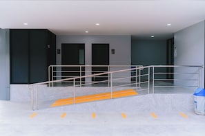 Un interior moderno con una escalera de metal, un bote de basura y dos puertas que indican 'Toilet' y 'Hombres'.