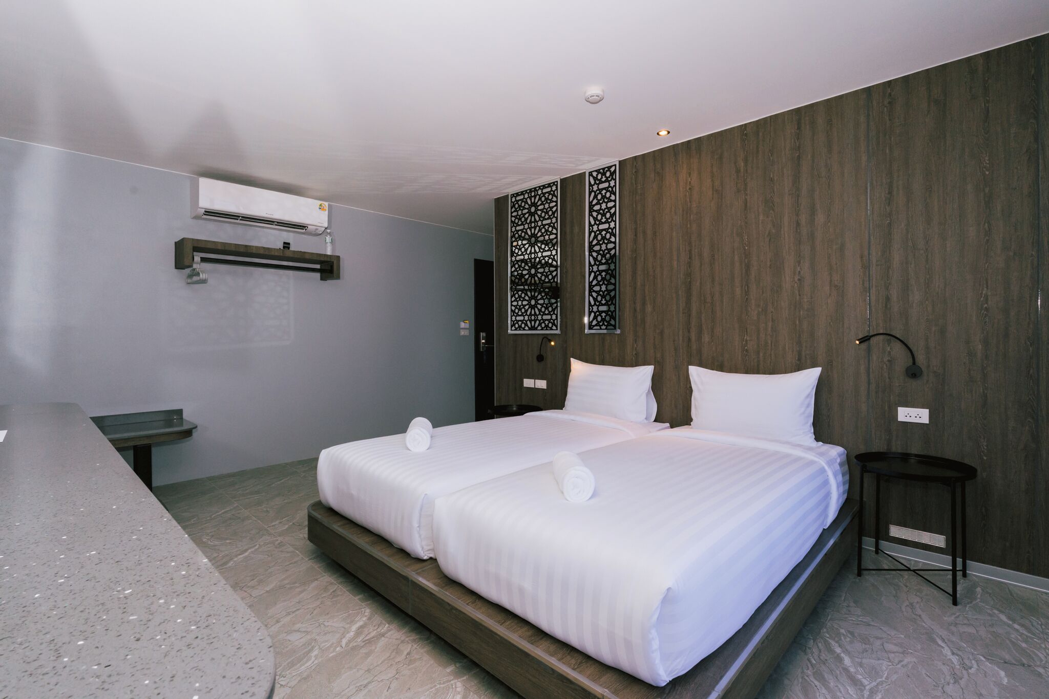A modern hotel room with a large bed, a desk, and a wall-mounted air conditioner.