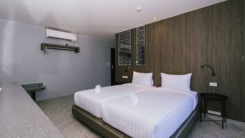 A modern hotel room with a large bed, a desk, and a wall-mounted air conditioner.