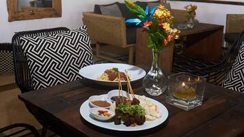 A dining table with a plate of food, a vase with flowers, and a candle.