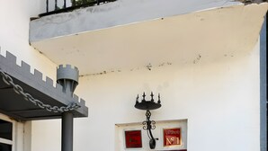 Entrada de un edificio con puerta roja, portón metálico y un cartel en la pared.
