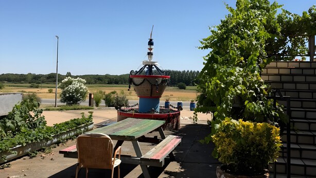 Un espacio al aire libre con mesa y sillas, una fuente decorativa y vistas del paisaje.