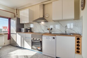 A modern kitchen with white cabinets, a stainless steel range hood, a built-in oven, and a dishwasher.