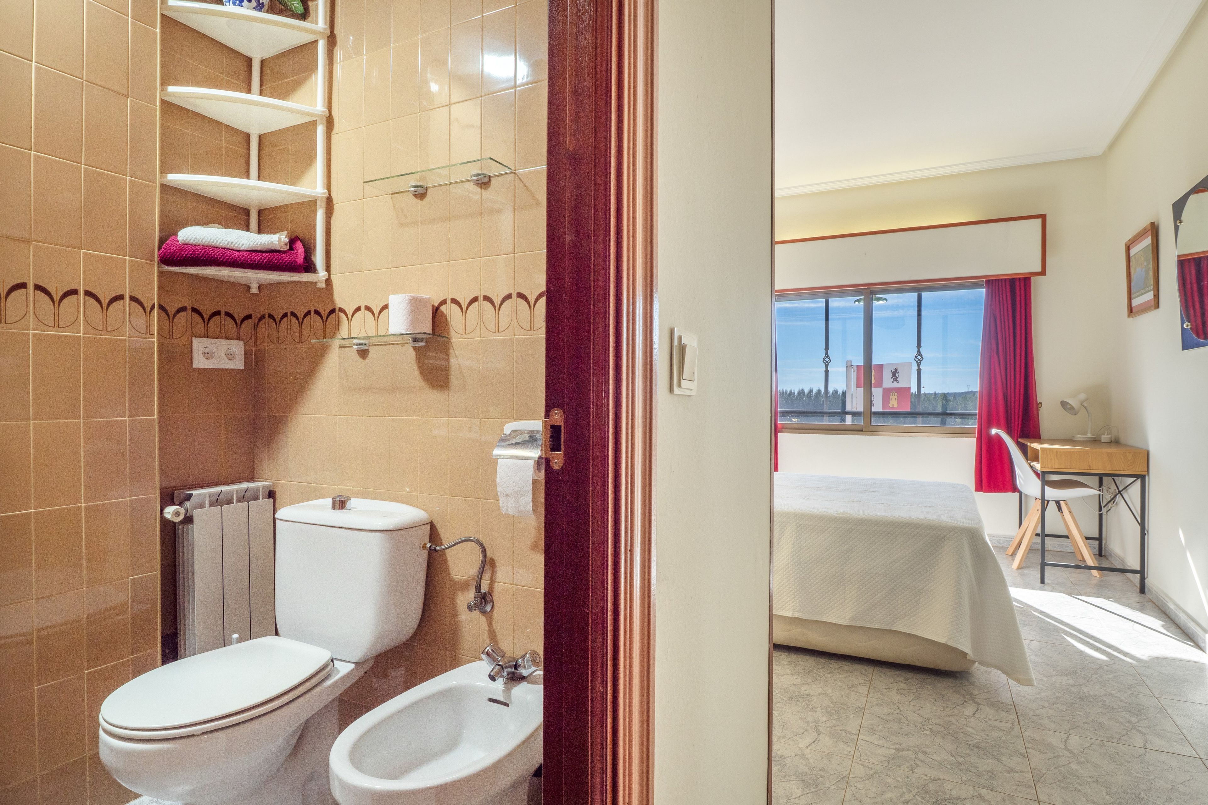 Un baño con inodoro, bidé y toalleros.