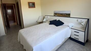 A hotel room with a large bed, bedside tables, a nightstand, and a framed picture on the wall.