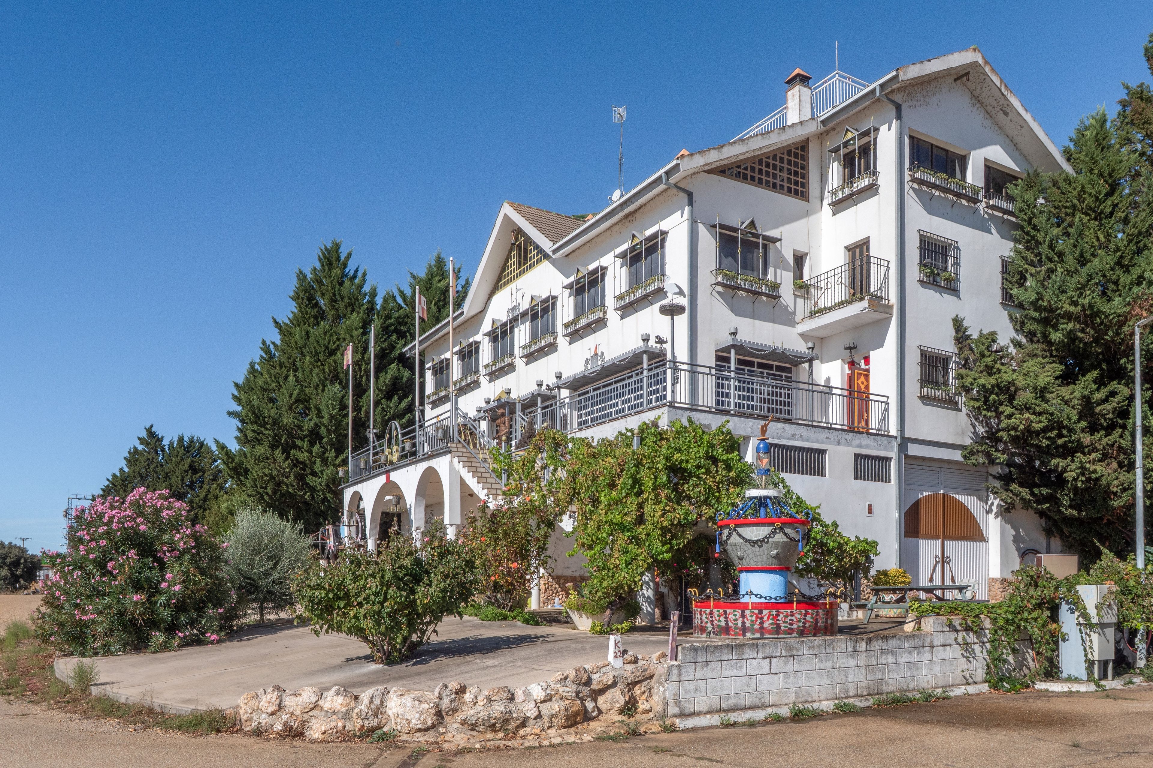 Un edificio de varios pisos con balcones, una pared de piedra y una fuente.