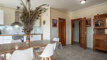 Una cocina moderna con encimera de mármol, una mesa de comedor con sillas y una decoración con plumas de pavo real.
