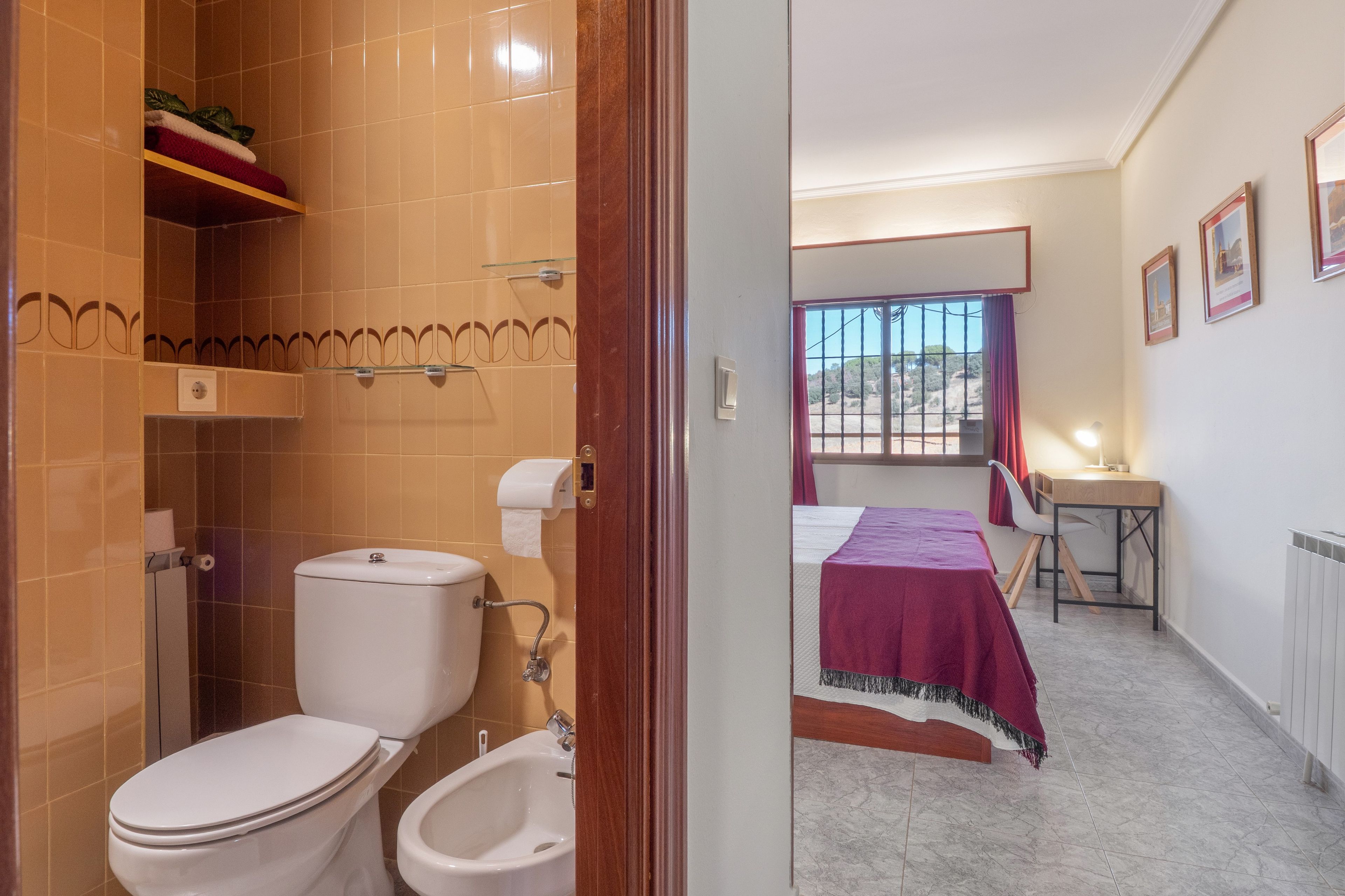 Une chambre d’hôtel avec salle de bain, un lit, un bureau et une fenêtre donnant sur un paysage agréable.