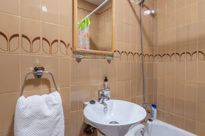 A bathroom with a white sink, a mirror, and a shower.