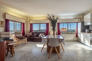 Ein geräumiges Wohnzimmer mit einer Couch, Sesseln, einem Esstisch und einer Pfauenfeder-Dekoration.