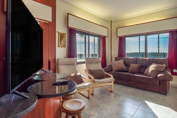 A living room with a television, a sofa, a chair, and a small table.