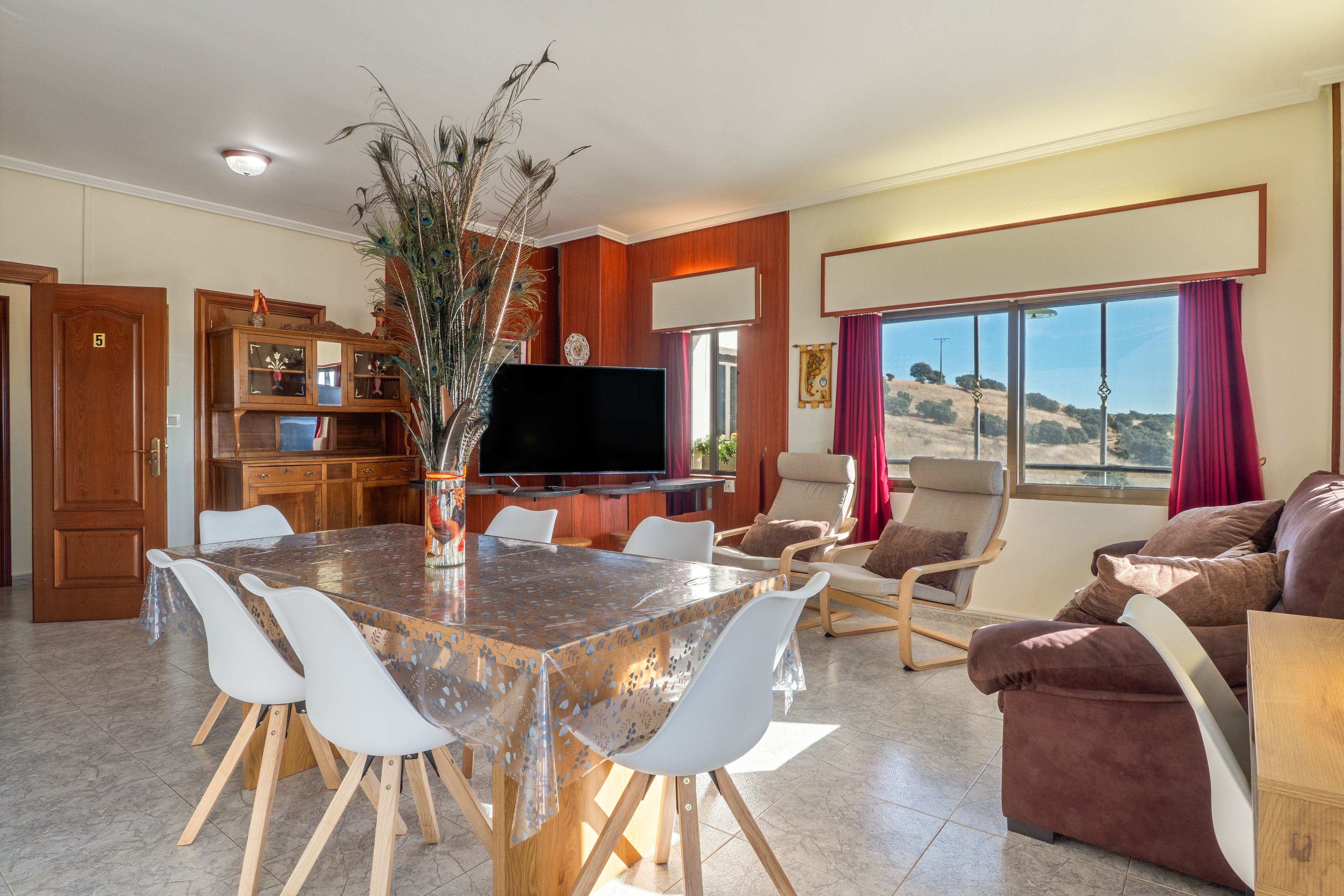Un'ampia zona giorno con tavolo da pranzo, sedie, divano e televisione.