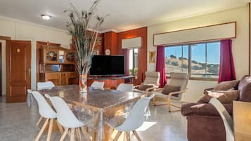 Un'ampia zona giorno con tavolo da pranzo, sedie, divano e televisione.