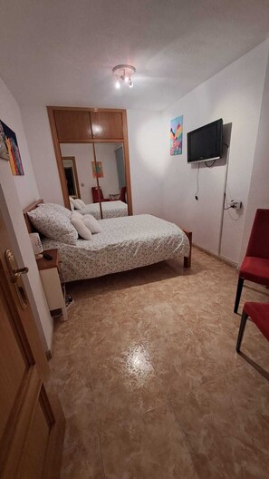 A bedroom with a bed, a television mounted on the wall, and a red chair. - Your home in Altea! 200 m from the beach / bright / 2 bedrooms / fully equipped / beautifully decorated. (Altea)
