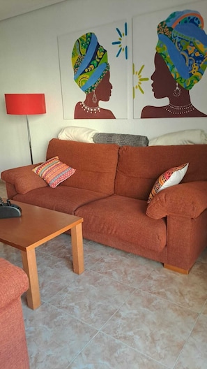 A living room with a brown sofa, a wooden coffee table, and a red floor lamp. - Your home in Altea! 200 m from the beach / bright / 2 bedrooms / fully equipped / beautifully decorated. (Altea)