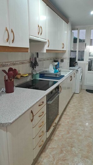 A kitchen with white cabinets, a black countertop, and a built-in oven. - Your home in Altea! 200 m from the beach / bright / 2 bedrooms / fully equipped / beautifully decorated. (Altea)