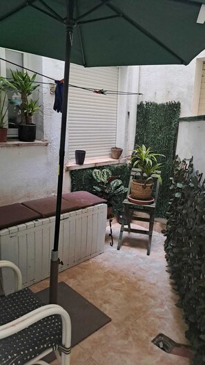 A patio area with a table, chairs, a bench, potted plants, and a green umbrella. - Your home in Altea! 200 m from the beach / bright / 2 bedrooms / fully equipped / beautifully decorated. (Altea)