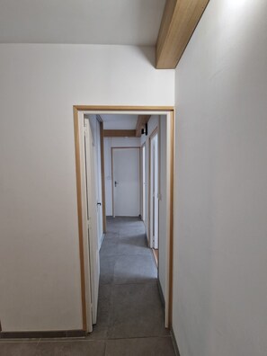 Ein schmaler Korridor mit Holzboden und weißen Wänden.