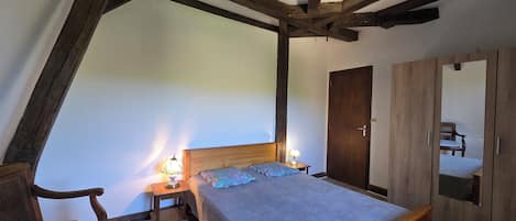 A bedroom with a wooden bed, two bedside tables with lamps, a wooden wardrobe, and a chair.