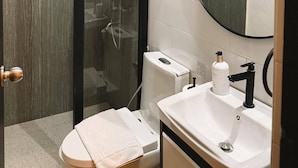 A modern bathroom with a glass-enclosed shower, a toilet, a sink with a mirror, and a towel rack. - Patio By Balai Norte La Union (San Juan)