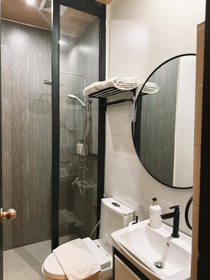A modern bathroom with a glass-enclosed shower, a toilet, a sink with a mirror, and a towel rack. - Patio By Balai Norte La Union (San Juan)