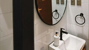 A bathroom with a white sink, a mirror, and a towel rack.