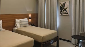 A hotel room with two beds, a desk, and a wall-mounted artwork. - Patio By Balai Norte La Union (San Juan)