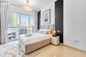Une chambre d’hôtel moderne avec un grand lit, une table de chevet avec une lampe, une œuvre d’art encadrée et une vue sur le paysage urbain par la fenêtre.
