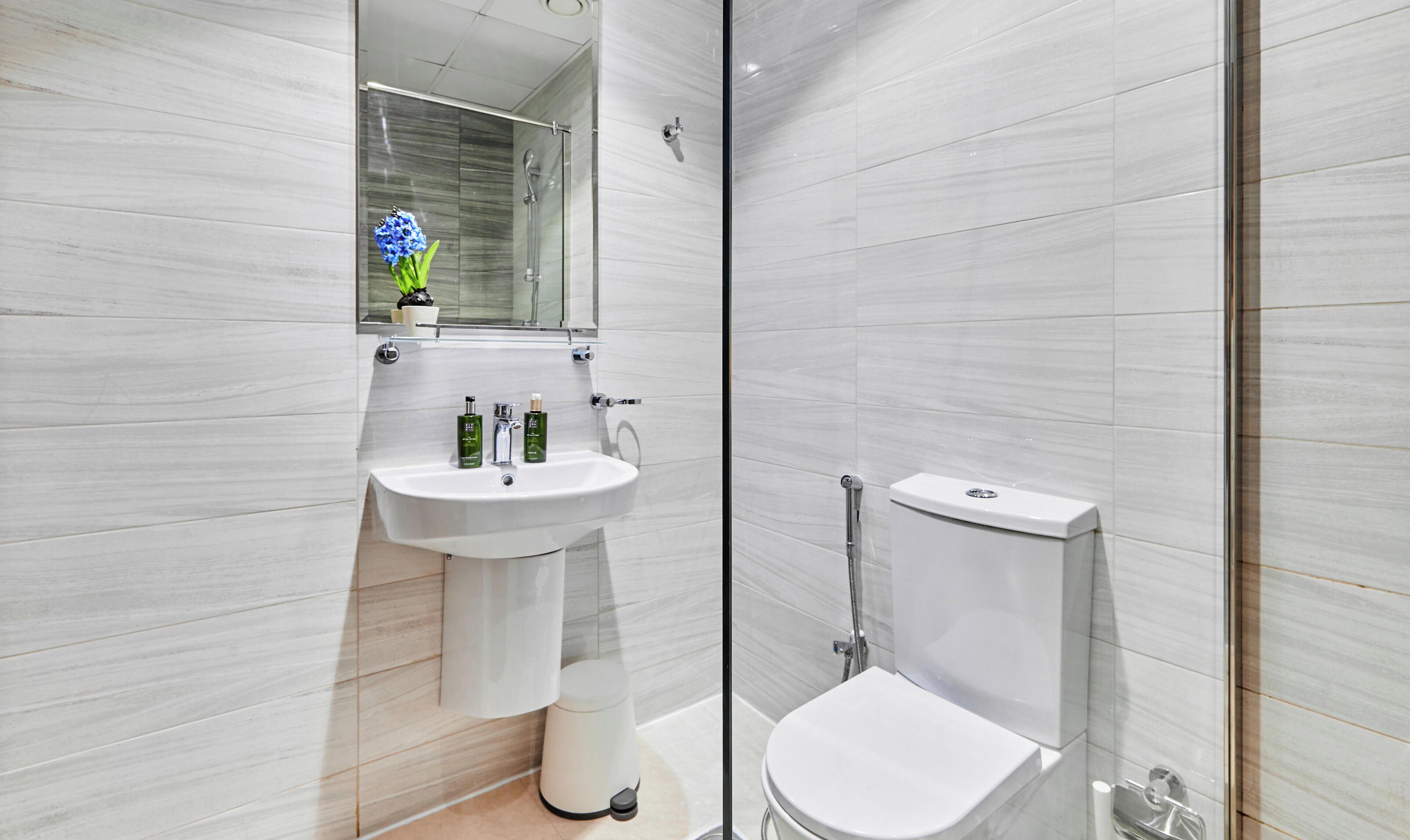 A modern bathroom with a white sink, toilet, and shower.