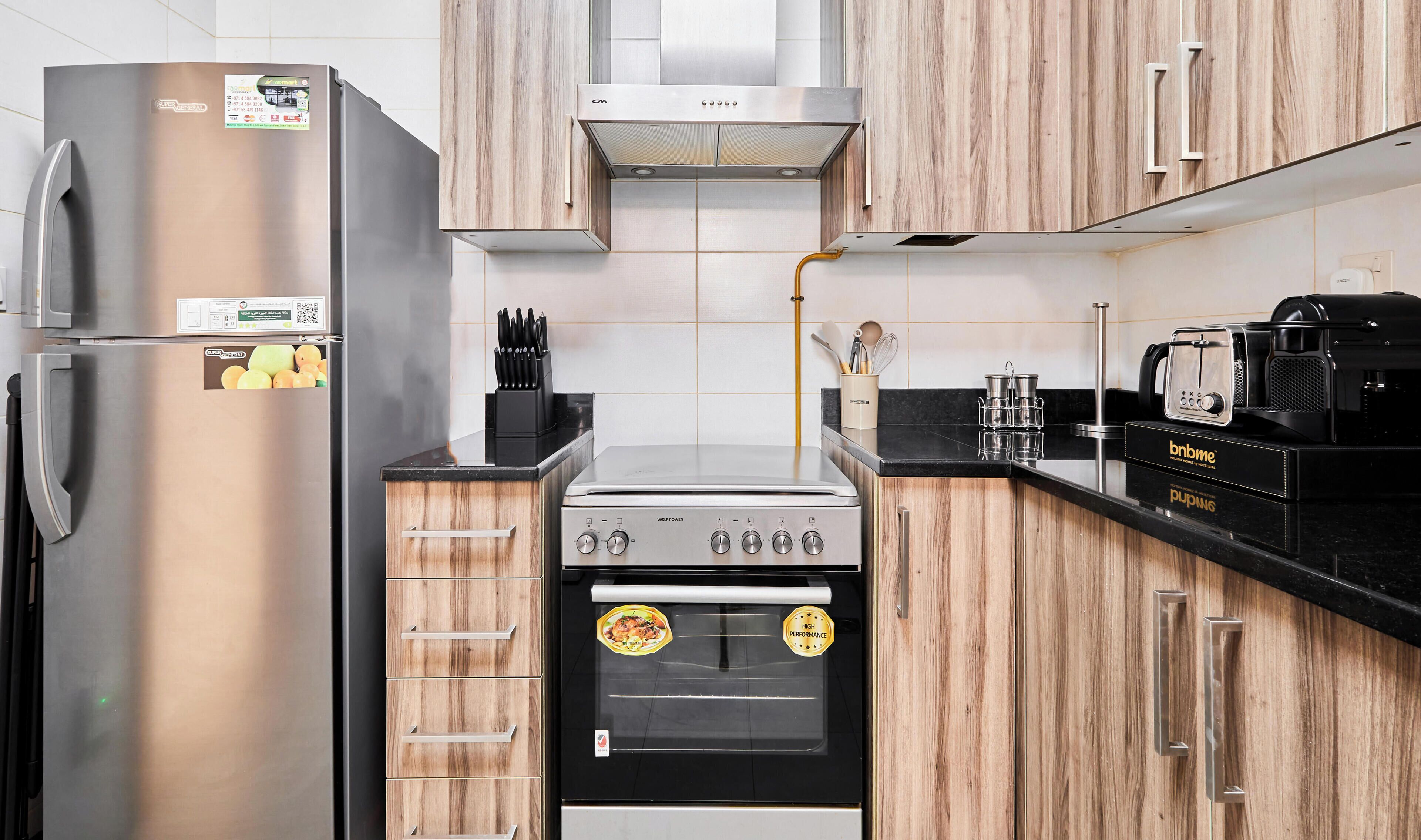 Una cocina con un refrigerador de acero inoxidable, una estufa Wolf Power y armarios de madera.