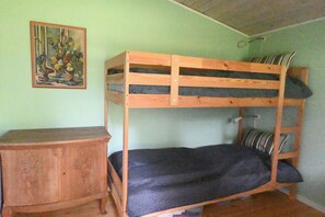 Ein Stockbett mit Holzrahmen, eine kleine Holzkommode und ein Bild an der Wand.