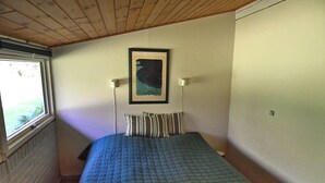A bedroom with a bed, a window, a painting on the wall, and a door. - A Charming Vacation Home Gem: Outdoor Amenities on the Property and a Beach Nearby (Kulhuse)