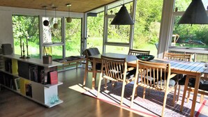 A modern kitchen with wooden furniture, large windows, and a view of greenery outside. - A Charming Vacation Home Gem: Outdoor Amenities on the Property and a Beach Nearby (Kulhuse)