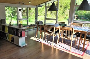 Ett modernt kök med trämöbler, stora fönster och utsikt över grönområden utanför.