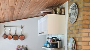 A kitchen with a wooden ceiling, hanging pots, a coffee machine, and a brick wall. - A Charming Vacation Home Gem: Outdoor Amenities on the Property and a Beach Nearby (Kulhuse)