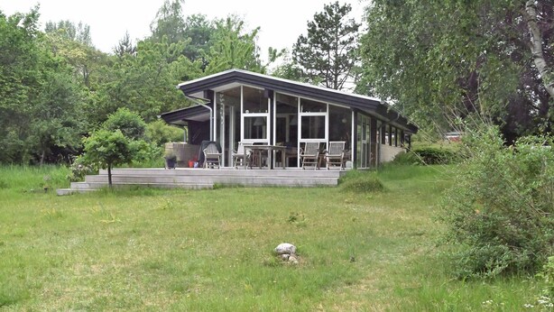 A modern house with a covered porch, surrounded by lush greenery. - A Charming Vacation Home Gem: Outdoor Amenities on the Property and a Beach Nearby (Kulhuse)