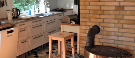 A kitchen with a brick wall, a wooden table, and a stove.