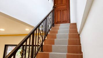 A staircase with alternating brown and grey steps, a wooden door at the top, and a black metal railing.