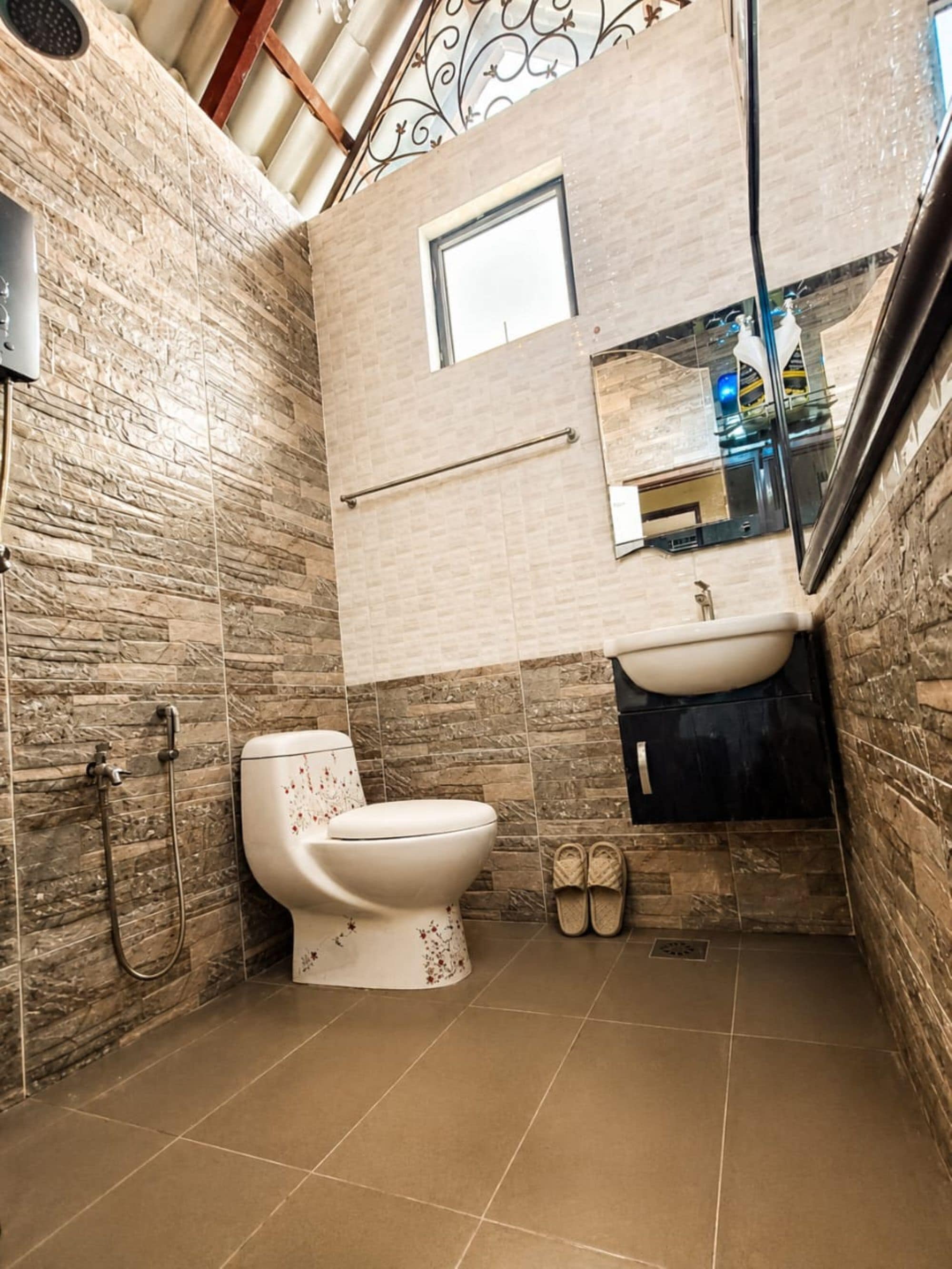 Et badeværelse med toilet, bruser og vask.