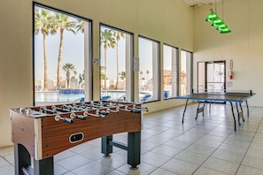 A pool table and foosball table in a room with large windows overlooking palm trees. - 5 Mi to Beach: Family Fun, Modern with Great Views (Port Isabel)