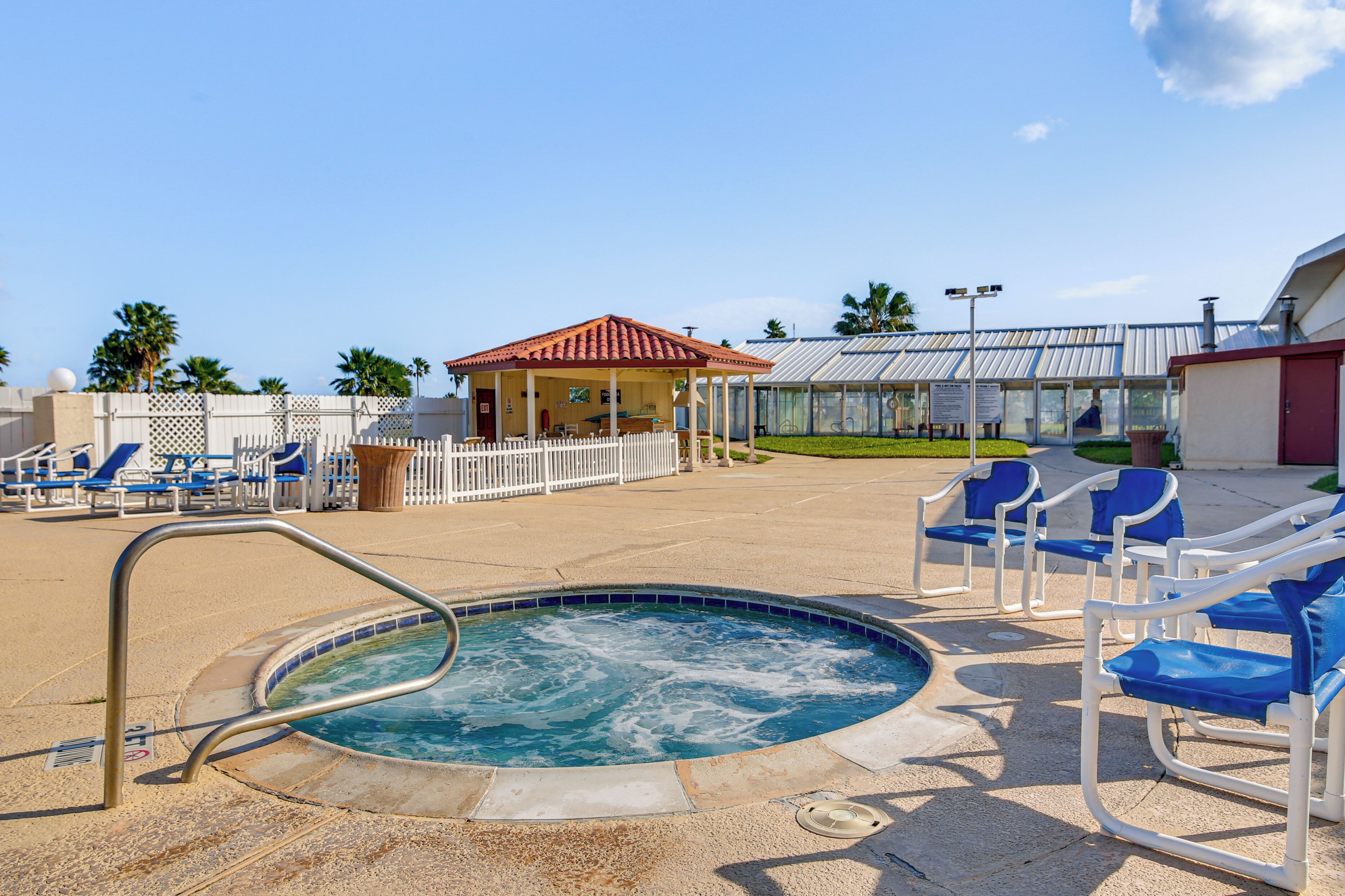 A pool area with lounge chairs, a hot tub, and a covered seating area.