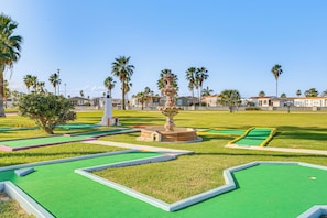 A miniature golf course with green artificial turf, palm trees, and a central fountain. - 5 Mi to Beach: Family Fun, Modern with Great Views (Port Isabel)