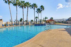 Ein Swimmingpool mit blauem Wasser, umgeben von Palmen und blauen Liegestühlen.