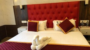 Una habitación de hotel con una cama grande, un cabecero rojo con capitonado y una colcha blanca y roja.